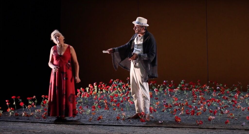 A man and a woman perform in a theater among the scenery