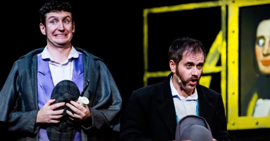 Two men with hats in their hands perform in the theater