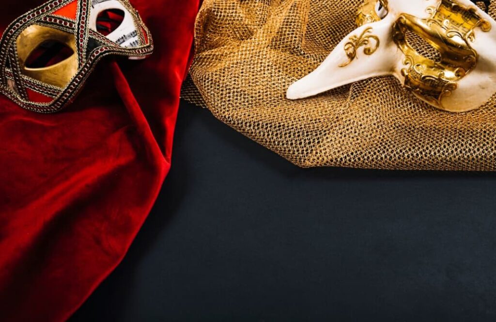 Ornate Venetian masks on red velvet and golden mesh, against a dark backdrop