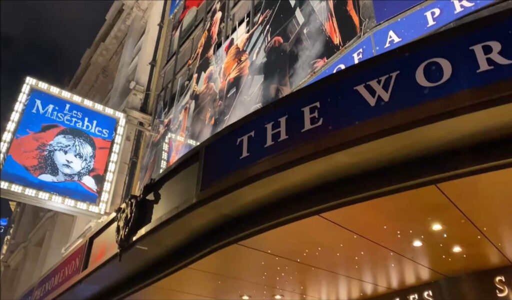 the building on the city street and signboard with les miserables on it