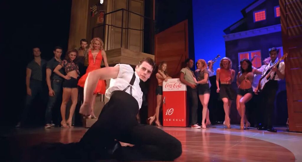 A performer dancing solo on a vibrant stage with onlookers