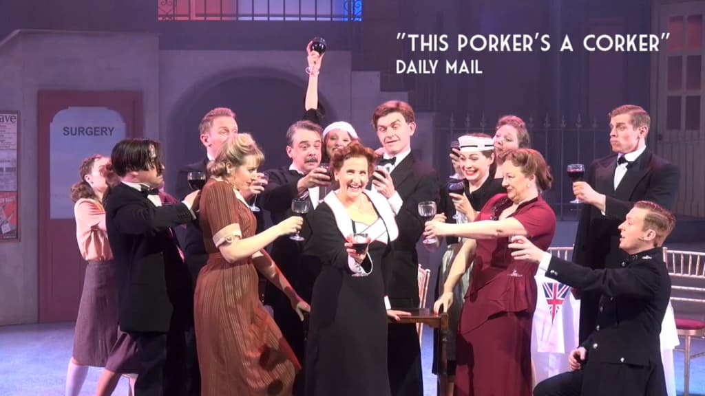 A theatrical ensemble raises wine glasses on stage