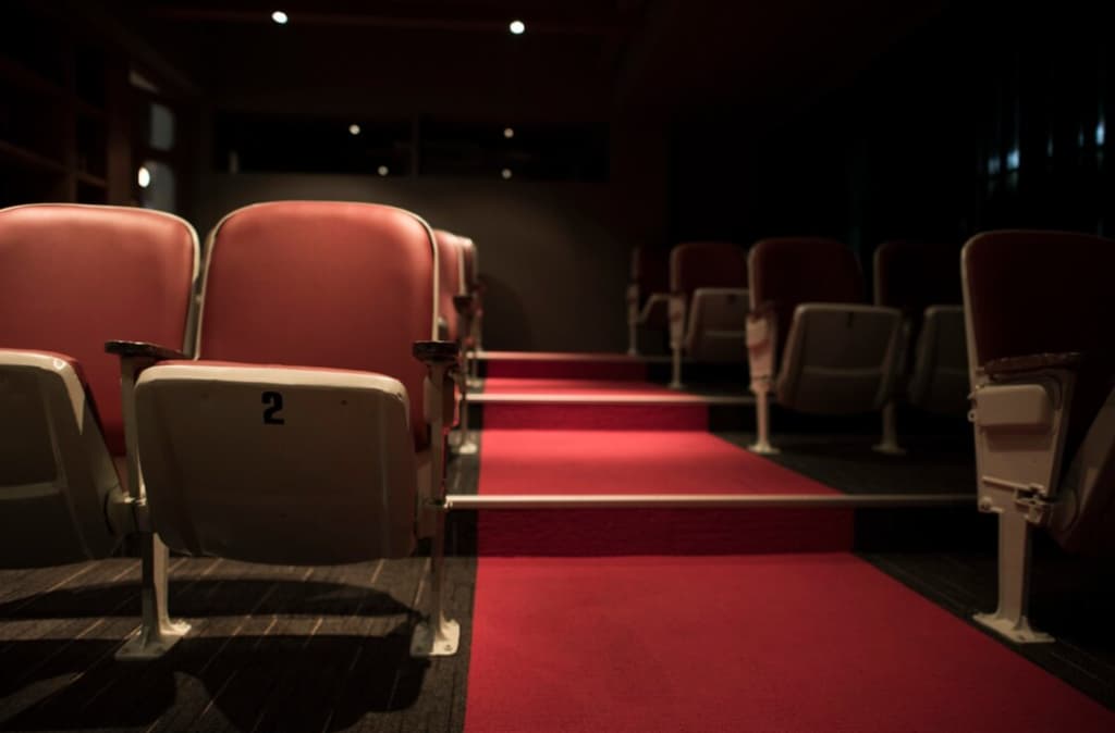 t theater aisle with red carpeting, rows of vintage white and pink seats