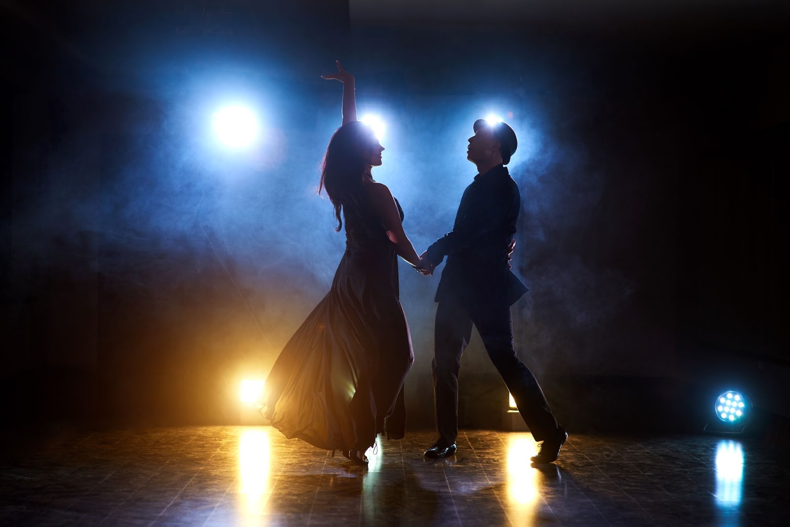 Skillful dancers performing in the dark room under the concert light and smoke