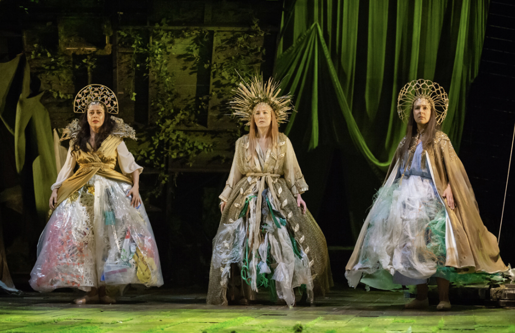 Three women standing on a stage, conveying a theatrical or performance setting