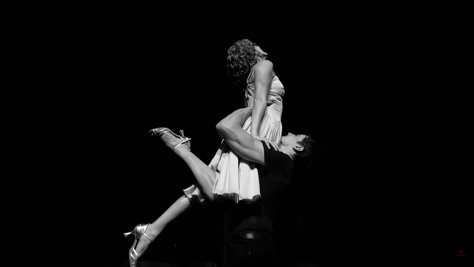 A dramatic black and white photo of a dance lift on stage