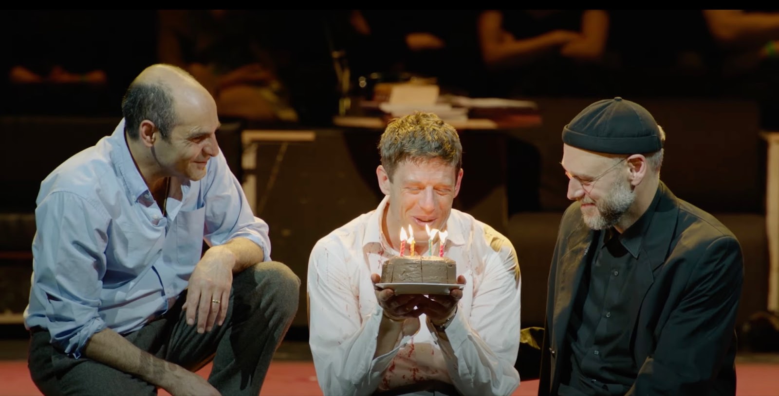 A man holding a cake next to other men on stage